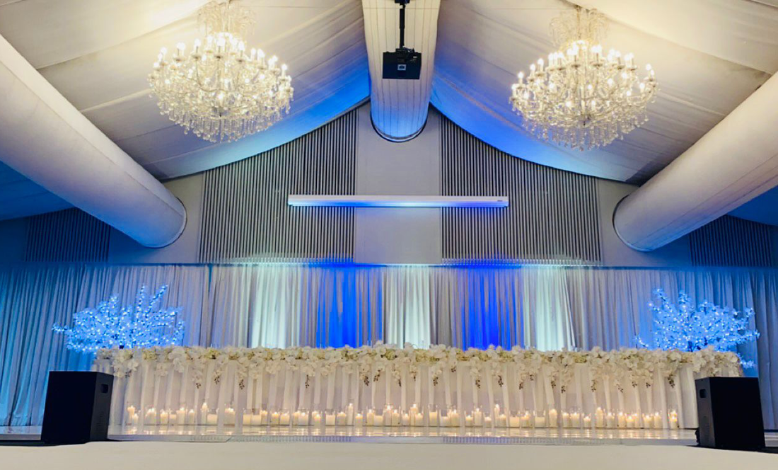 Uplighting styled at a wedding directly behind bridal table with LED trees set to the same colour scheme